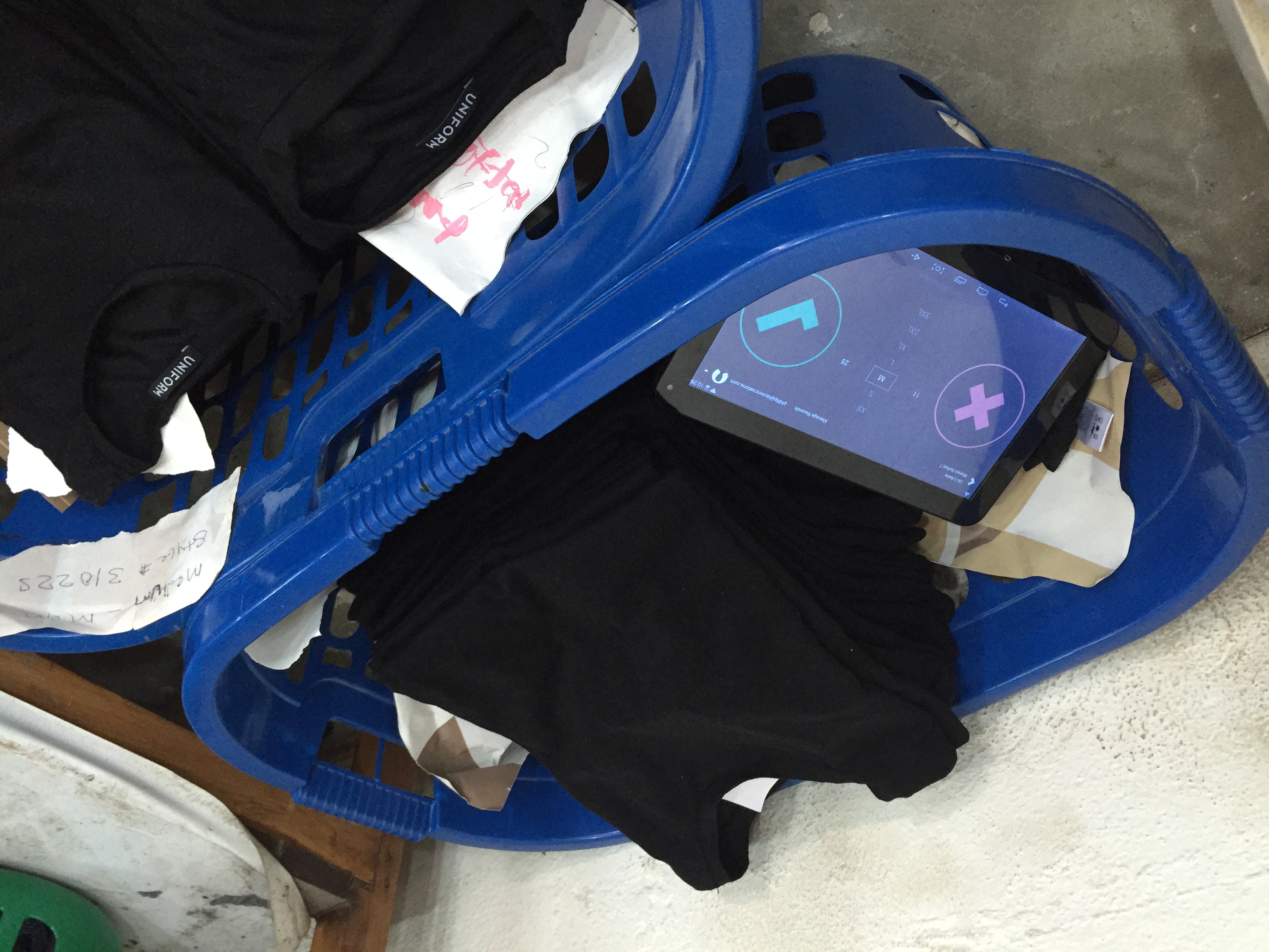 The production-line tablet interface alongside garments and paper labels, built for use over a 3G connection.